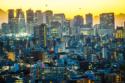 Illuminated cityscape against sky during sunset