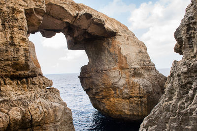 Wied il mielah canyon and natural arch over the sea in gozo, malta