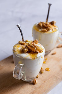 Cups of yogurt with honey and nuts on white background