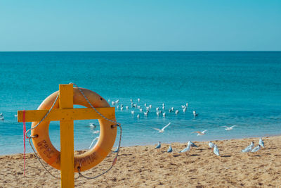 Deck chairs on beach against clear blue sky