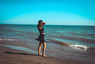 Full length of man standing on beach against clear sky