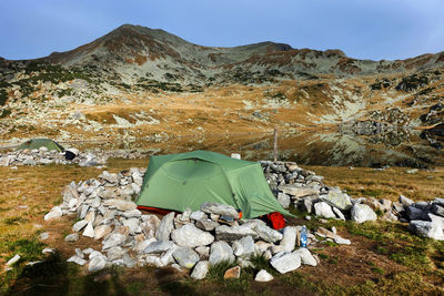 Tent on rocky mountain against sky