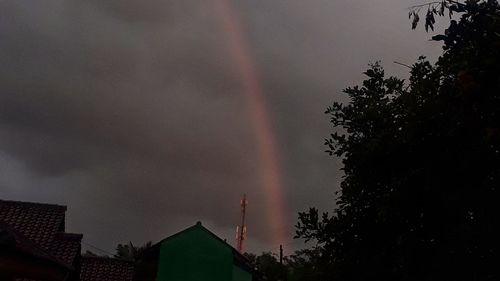 Low angle view of rainbow over buildings against sky