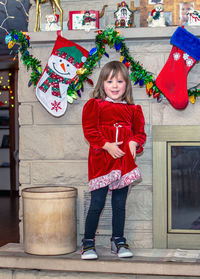 Girl in red poses by christmas stockings