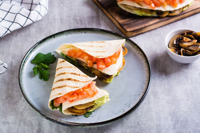 Grilled flatbread stuffed with avocado, mushrooms, tomatoes and parsley on a plate