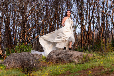 Portrait of young woman standing on rock in wedding dress