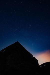 Low angle view of silhouette mountain against sky at night