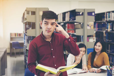 Young man thinking while standing in library