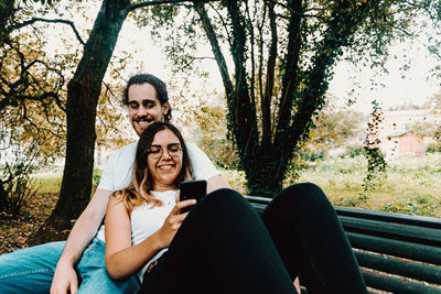 Portrait of smiling young woman sitting at park