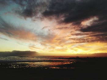 Scenic view of sea against dramatic sky during sunset