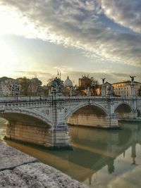 Bridge over river against cloudy sky