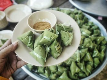 Cropped image of woman holding fresh chicken meat wrapped in banana leaves