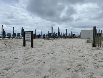 Hooded beach chairs on sand against sky