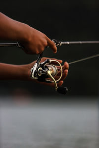 Close-up of hand holding fishing rod.