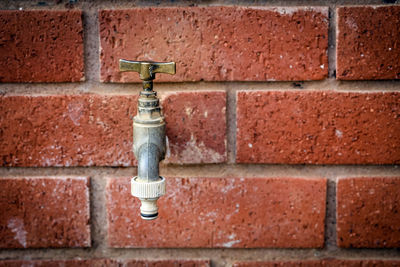 Close-up of tap on brick wall