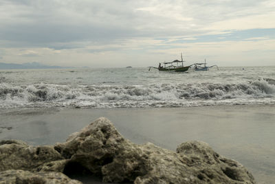Sailboat on sea shore against sky