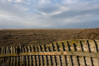 Wooden fence on landscape against sky