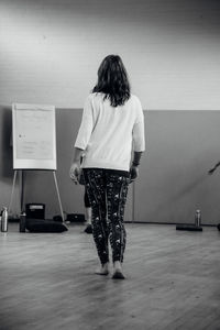 Rear view of woman standing against wall at home