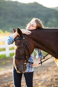 Young woman with horse standing on field