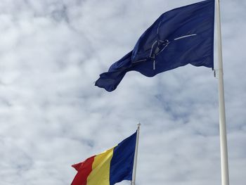 Low angle view of flags waving against sky