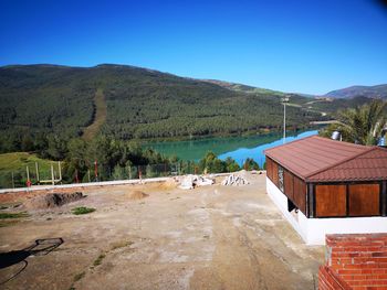 Scenic view of houses and mountains against clear blue sky