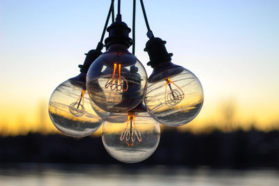 Close-up of illuminated light bulb against sky