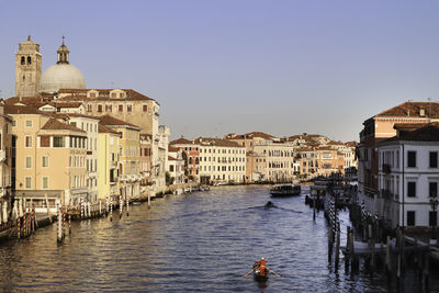 Buildings by venice lagoon against clear sky