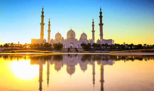 Mosque reflecting on lake during sunset