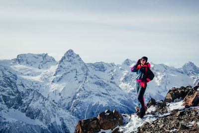 Man standing on snowcapped mountain against sky