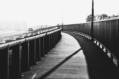 Footbridge in city against clear sky