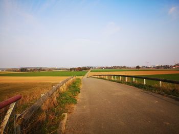 Road amidst field against sky