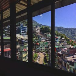 Buildings in town against sky seen through window