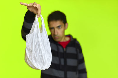 Portrait of young man standing against green background