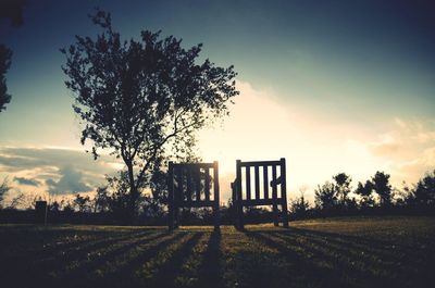 Empty chairs on field against sky during sunset