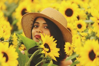 Portrait of beautiful young woman amidst sunflowers