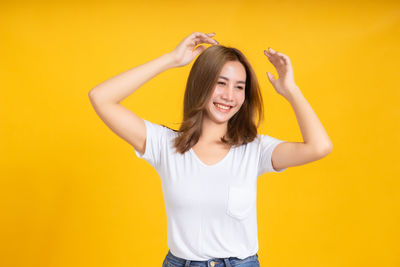 Portrait of smiling young woman against yellow background