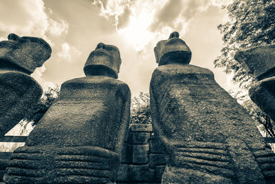 Low angle view of buddha statue against cloudy sky