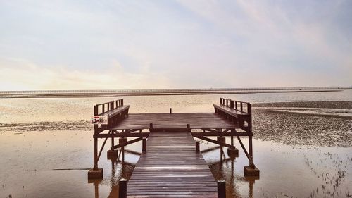 Pier over sea against sky during sunset