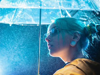 Close-up of young woman carrying umbrella while standing outdoors during rainy season