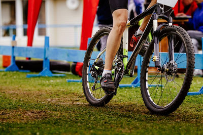 Low section of man riding bicycle on grass