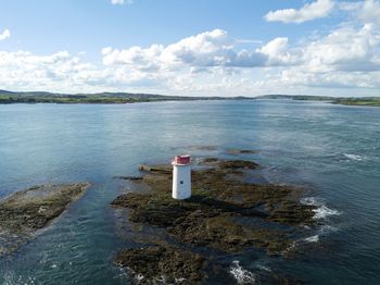 Lighthouse by sea against sky