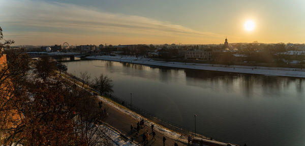 High angle view of river by buildings against sky during sunset