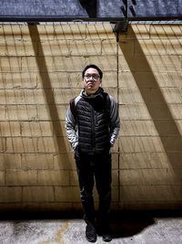 Portrait of young man standing against wall