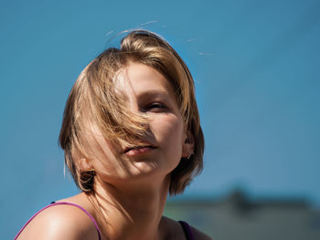 Portrait of young woman with a short haircut against the background of sky, the wind
