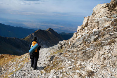 Rear view of hiker walking on mountain trail