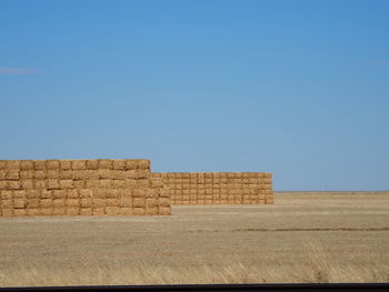 Stone wall on field against clear blue sky