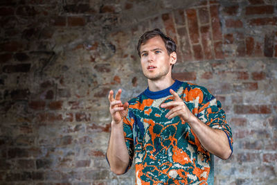 Portrait of young man standing against wall