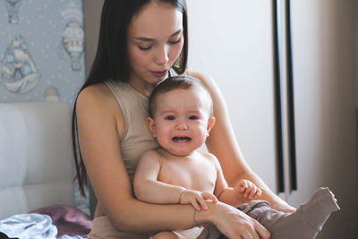 Portrait of cute girl sitting on bed at home