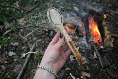 Cropped hand of woman holding wood over fire