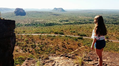 Rear view of woman standing on landscape against sky